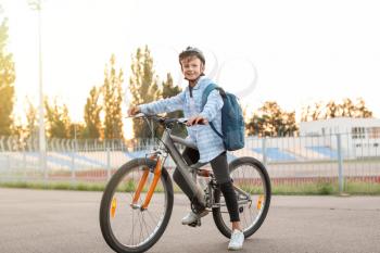 Cute boy riding bicycle outdoors�