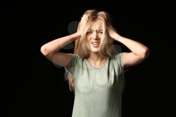 Stressed young woman on dark background�