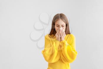 Young woman suffering from allergy on light background�
