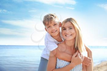 Portrait of happy mother and son on sea beach�