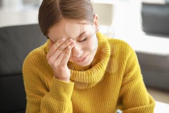 Young woman suffering from headache at home�