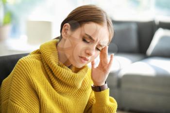 Young woman suffering from headache at home�