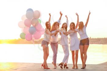 Beautiful young women with champagne at hen party near river�