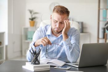 Young man suffering from headache in office�