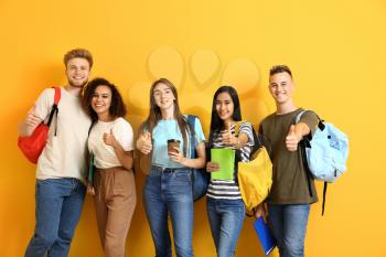 Group of students showing thumb-up gesture on color background�