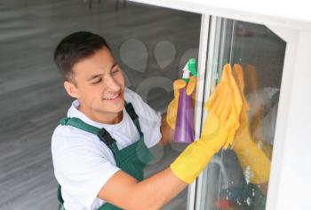Young man cleaning window at home�