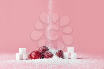 Sprinkling of sugar onto fresh strawberries against color background�