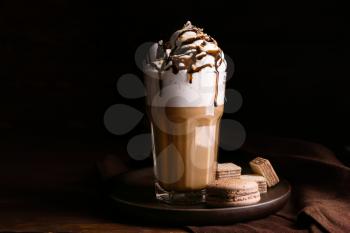 Glass of tasty frappe coffee with sweets on wooden table�