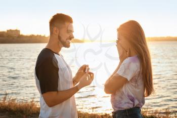 Young man proposing to his beloved near river�