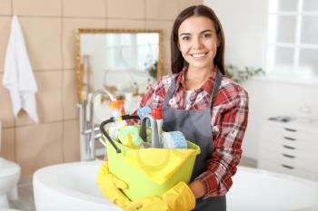 Beautiful young woman with cleaning supplies in bathroom�