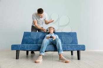 Little boy playing videogame and ignoring his angry father at home�