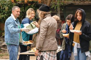 Volunteers giving food to homeless people outdoors�