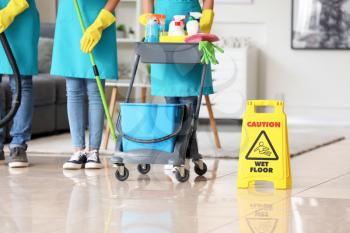 Team of janitors with cleaning supplies in room�