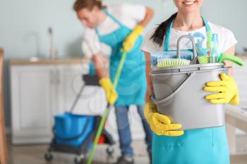 Female janitor with cleaning supplies in kitchen�