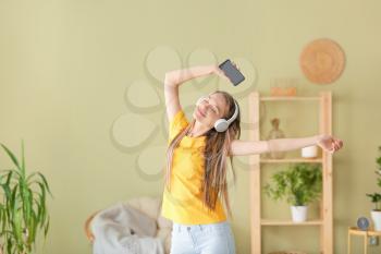 Dancing woman listening to music at home�