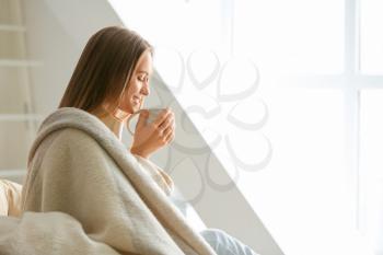 Young woman with cup of hot tea resting at home�