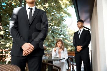 Young businesswoman with bodyguards in cafe�