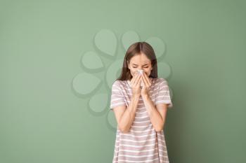 Young woman suffering from allergy on color background�