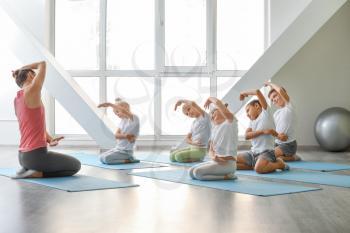Little children practicing yoga with instructor in gym�