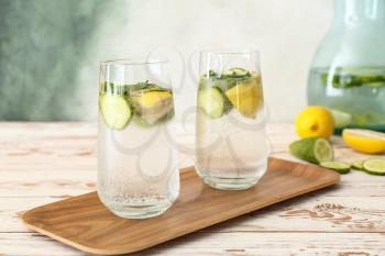 Glasses of cold cucumber water on white table�