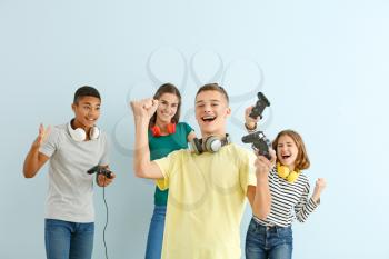 Teenager boy with friends playing video games against light background�