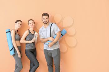 Group of people with yoga mats near color wall�