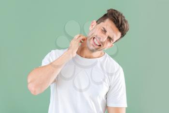 Scratching allergic young man on color background�