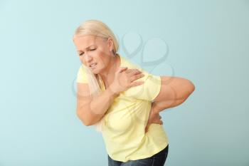 Mature woman suffering from back pain on color background�