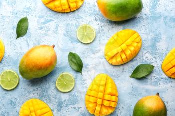 Sweet ripe mangoes and lime on color background�