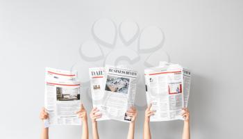 Female hands with newspapers on light background�