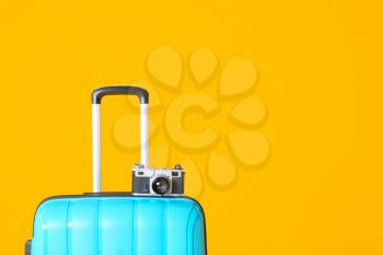 Packed suitcase and photo camera on color background. Travel concept�
