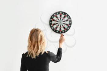 Young woman playing darts indoors�