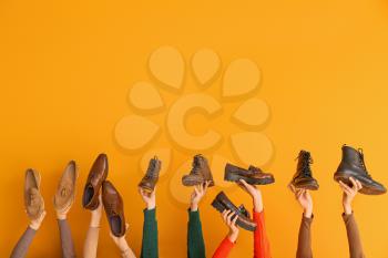 Many hands with different stylish shoes on color background�