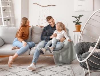 Happy young family sitting on sofa at home�