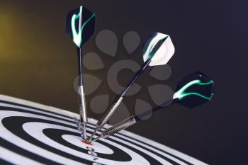 Dartboard with hit bullseye on dark background, closeup�