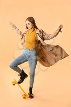 Stylish hipster girl with skateboard on color background�