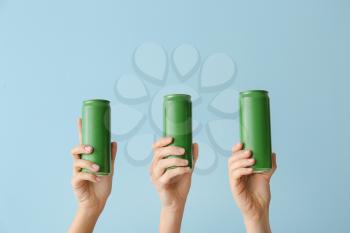 Hands with cans of beer on color background�
