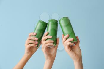 Hands with cans of beer on color background�