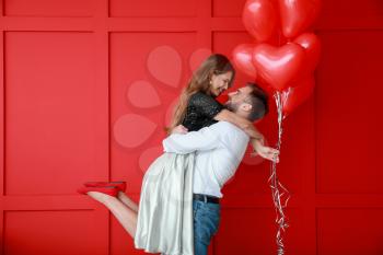 Happy young couple with heart-shaped balloons on color background. Valentine's Day celebration�