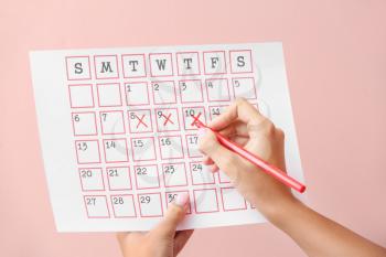 Woman with menstrual calendar on color background�
