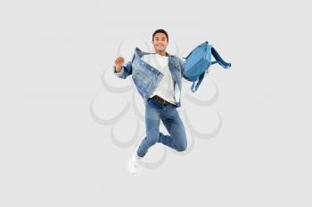 Jumping African-American teenager boy with backpack on white background�