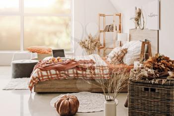 Stylish interior of room with big comfortable bed and autumn decor�