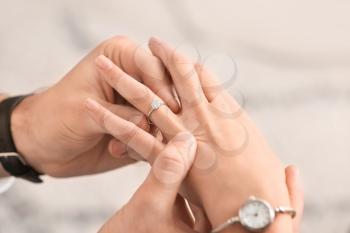 Young man putting ring on finger of his fiancee after marriage proposal, closeup�
