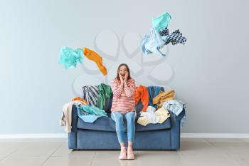 Excited woman with heap of clothes on sofa indoors�