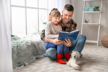 Cute little girl with father reading book at home�