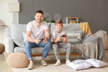 Father and his little son playing video games at home�