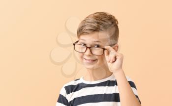Cute little boy with eyeglasses on color background�