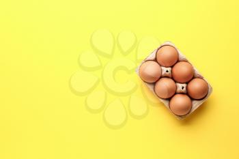 Package with fresh eggs on color background�