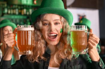Young woman with beer celebrating St. Patrick's Day in pub�
