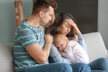Young father with baby and wife suffering from postnatal depression at home�